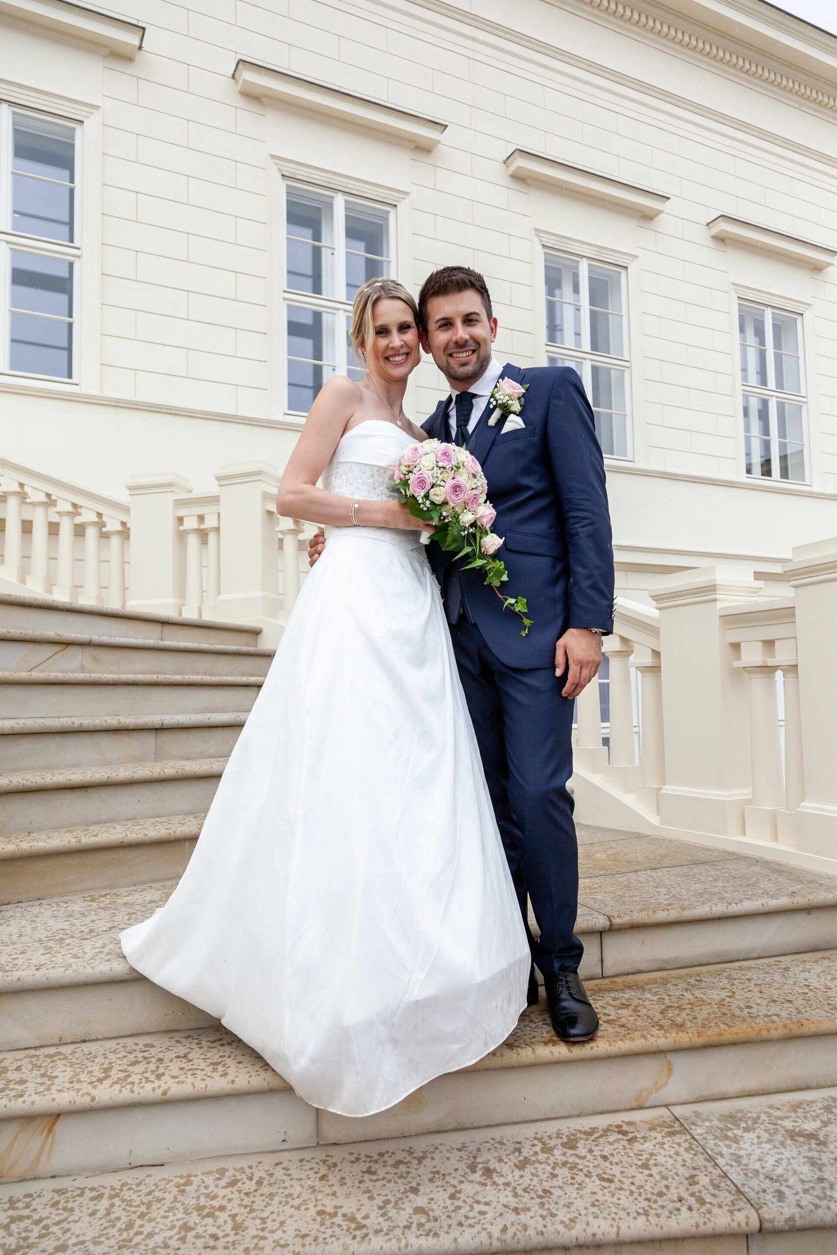 Brautpaar auf der Schlosstreppe – Bräutigam im dunkelblauen Hochzeitsanzug